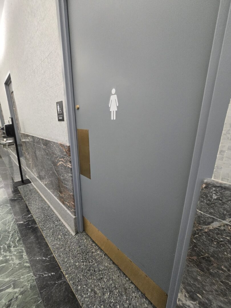 A photo of a women's restroom door, showcasing the lack of automatic capabilities, despite being labeled as "accessible"